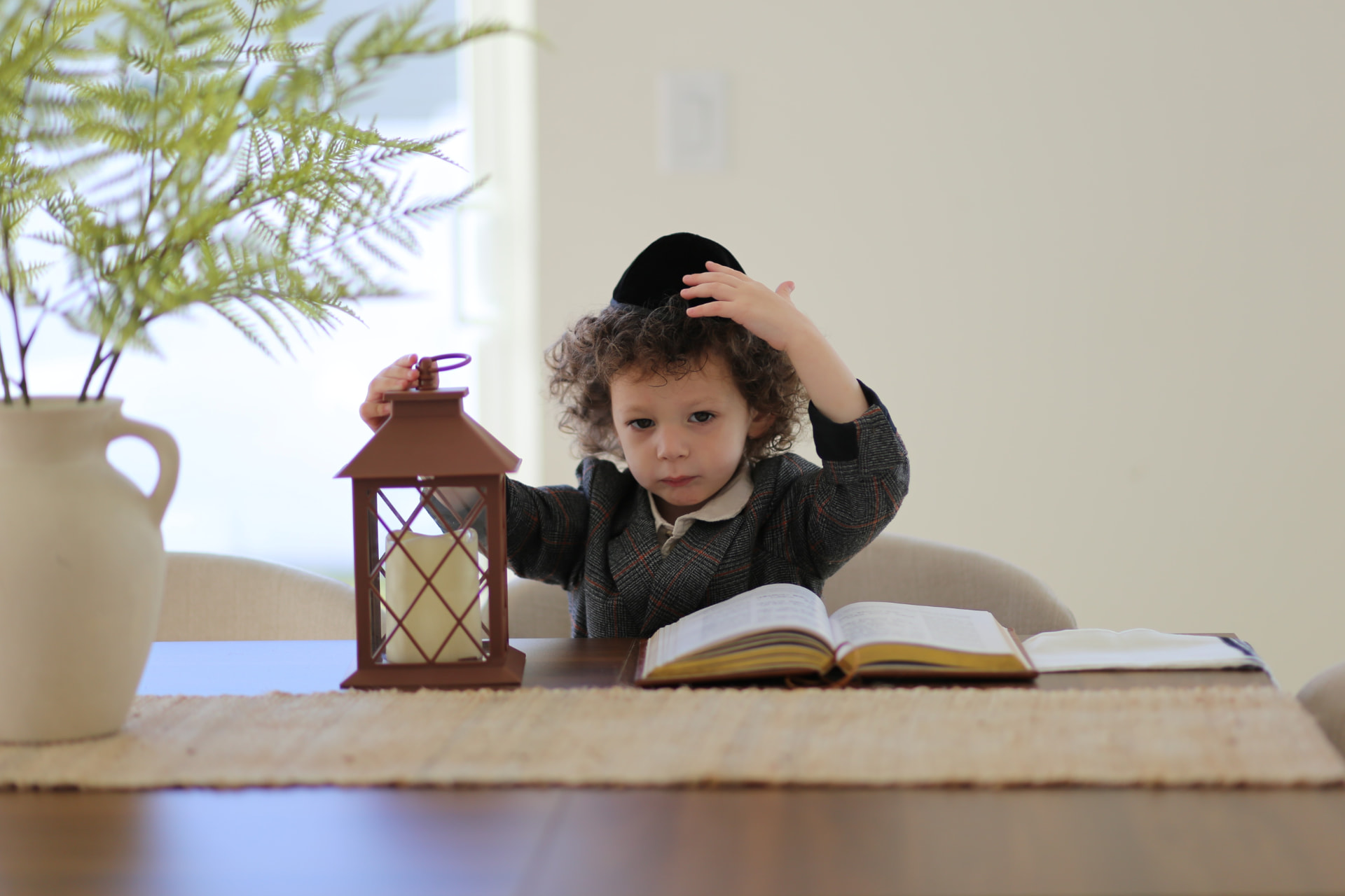 A boy with his book and lantern at the table.