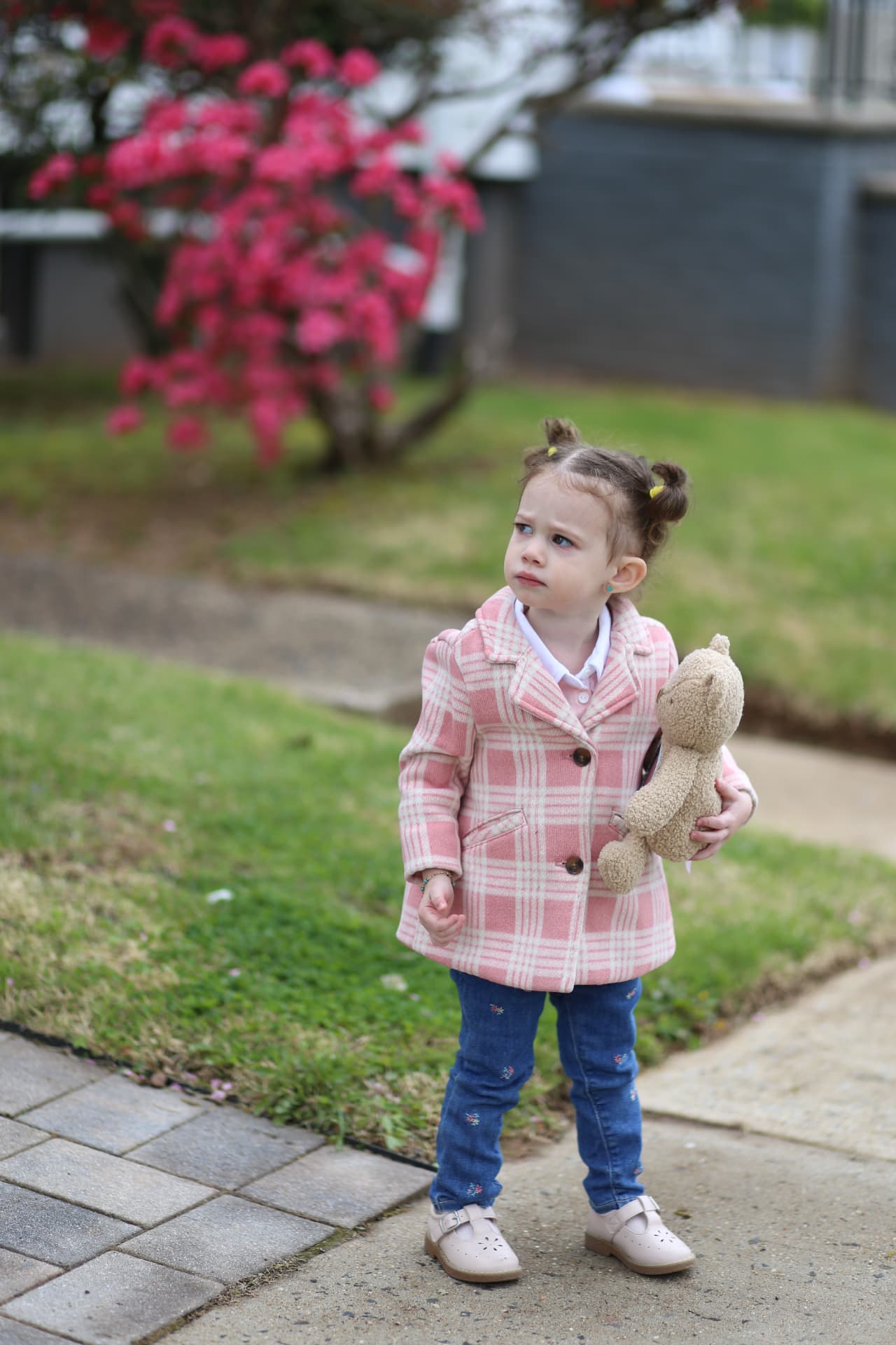 Teddy under her arm, the pink tree in bloom behind her.