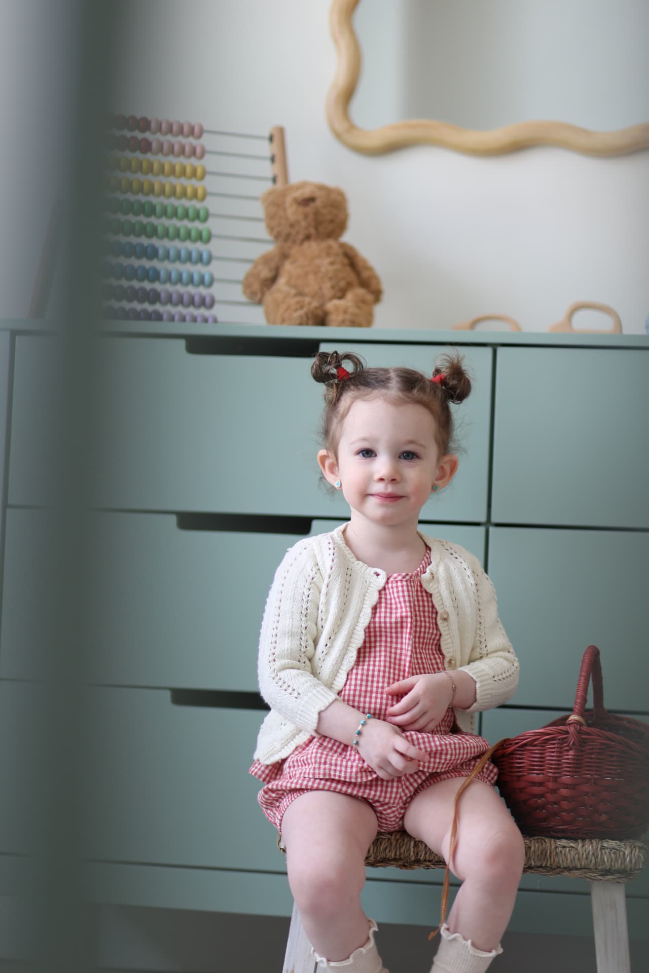 A little girl in pink seated in her playroom.