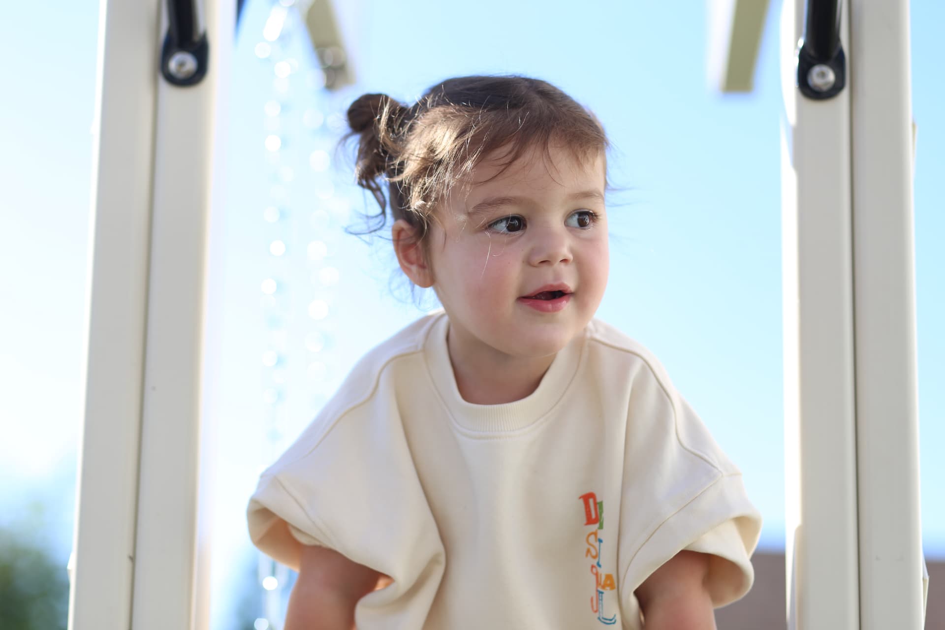 A little girl smiling on the backyard playset.