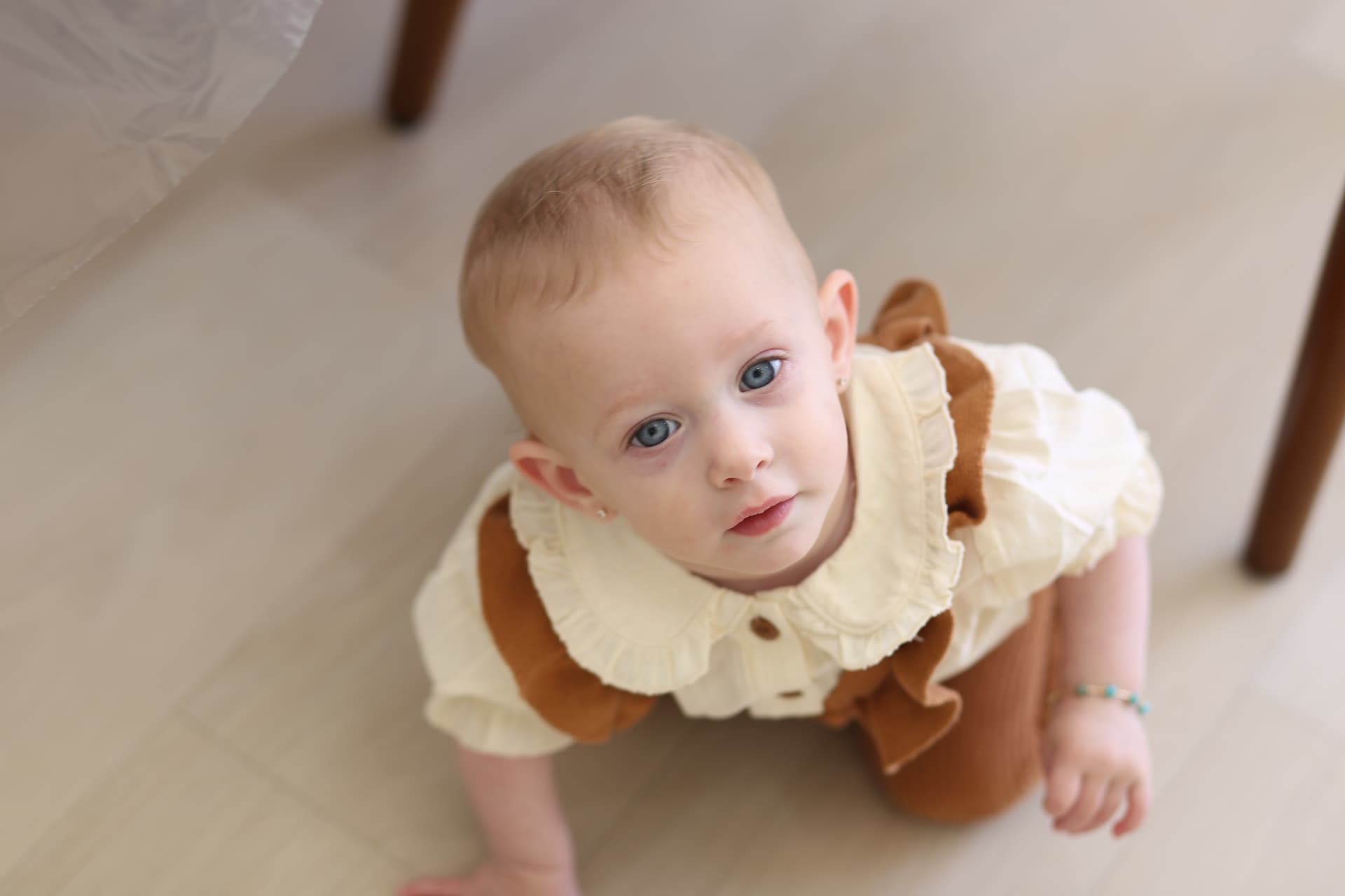 A baby crawling under the kitchen table.