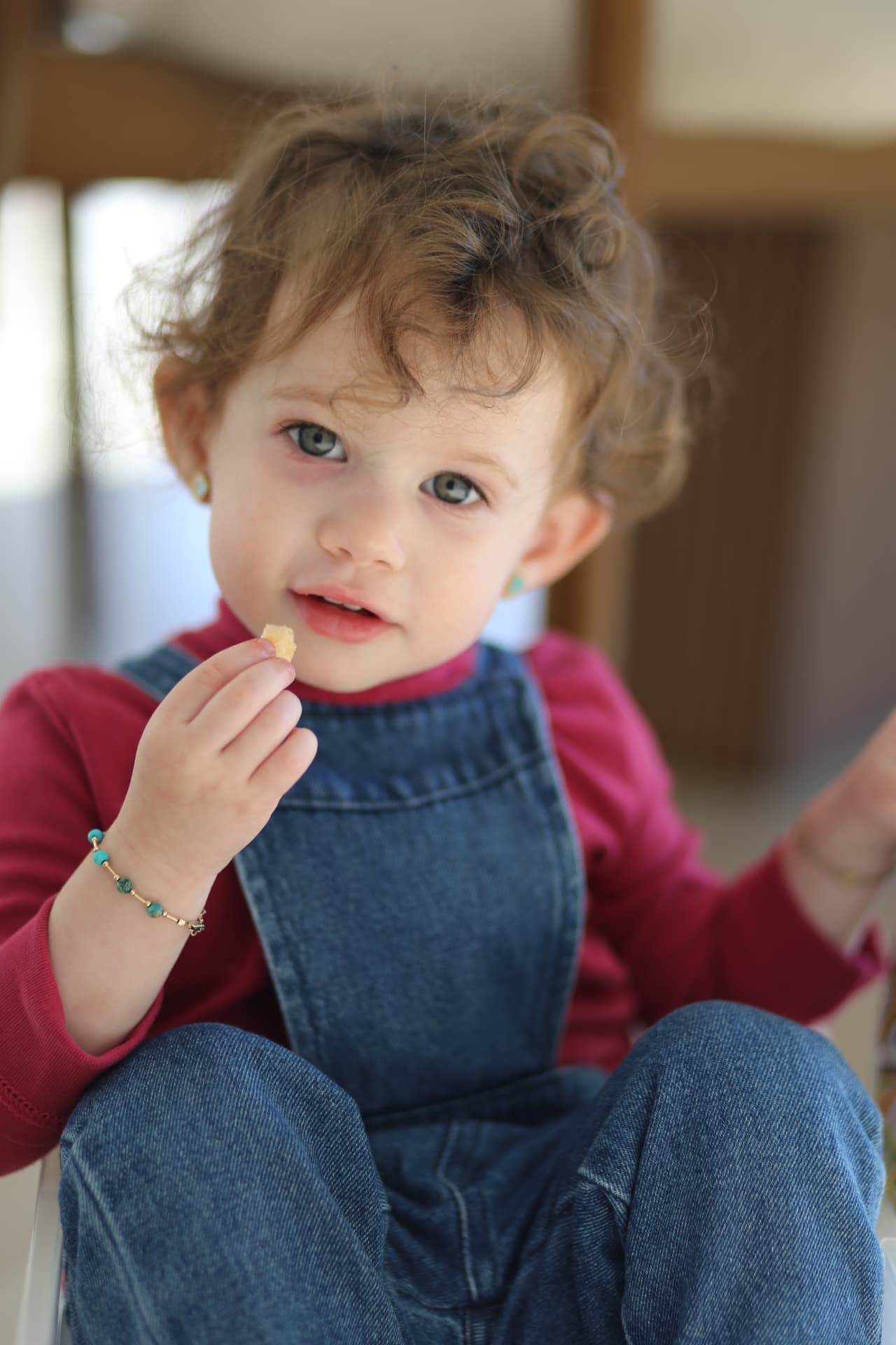 Curls, denim, and a snack held tight.