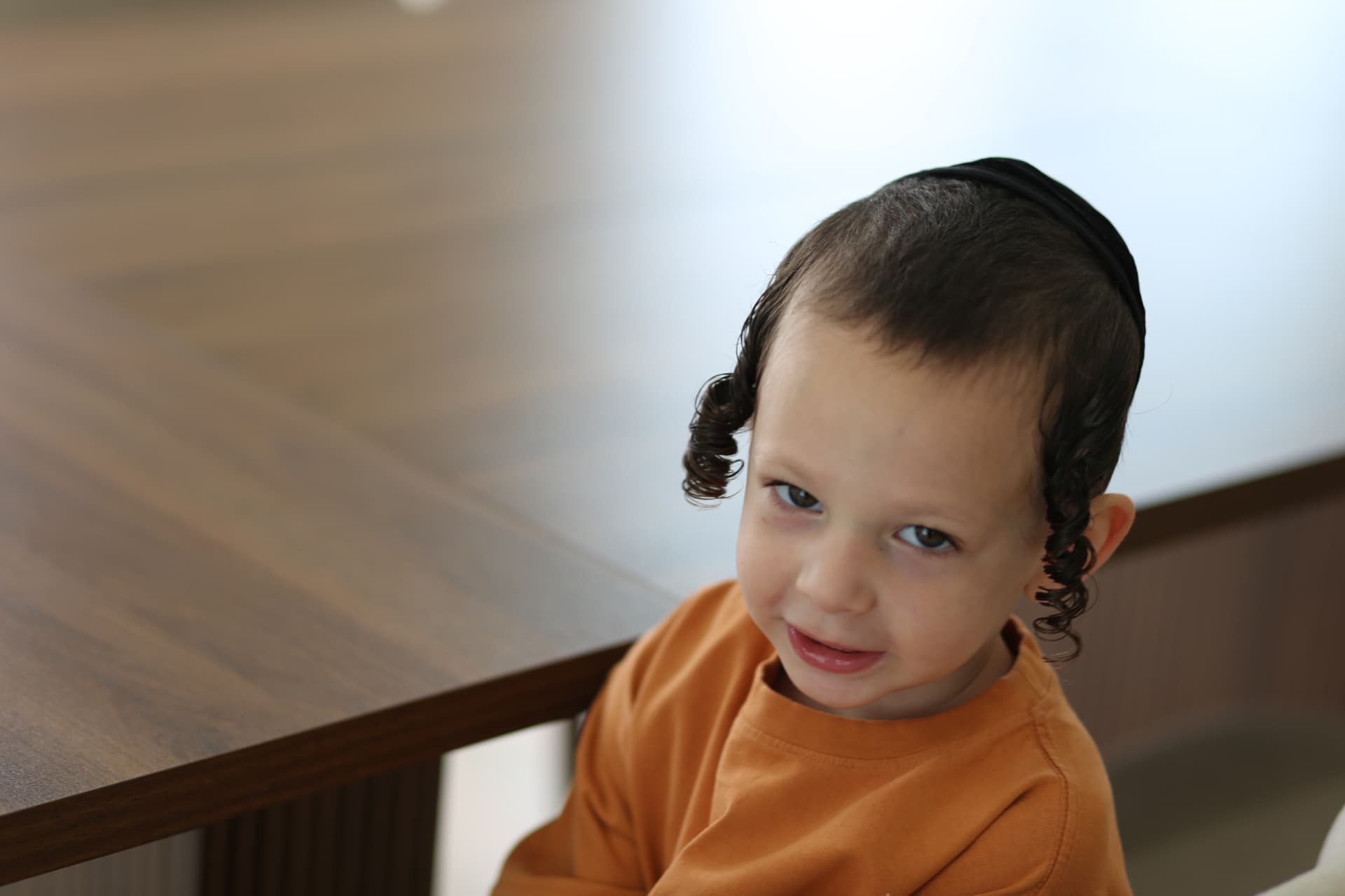 A shy little smile from beside the dining table.