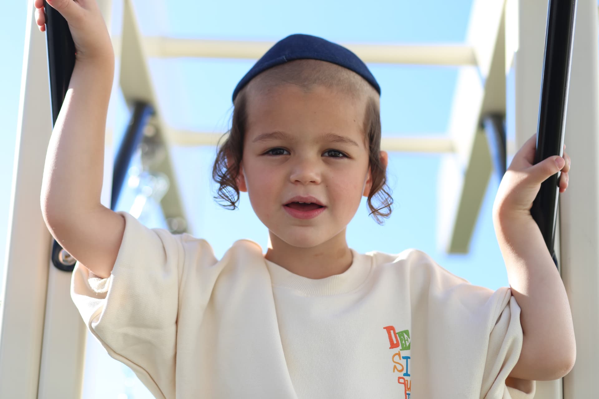 A boy gripping the playset bars, ready to climb.