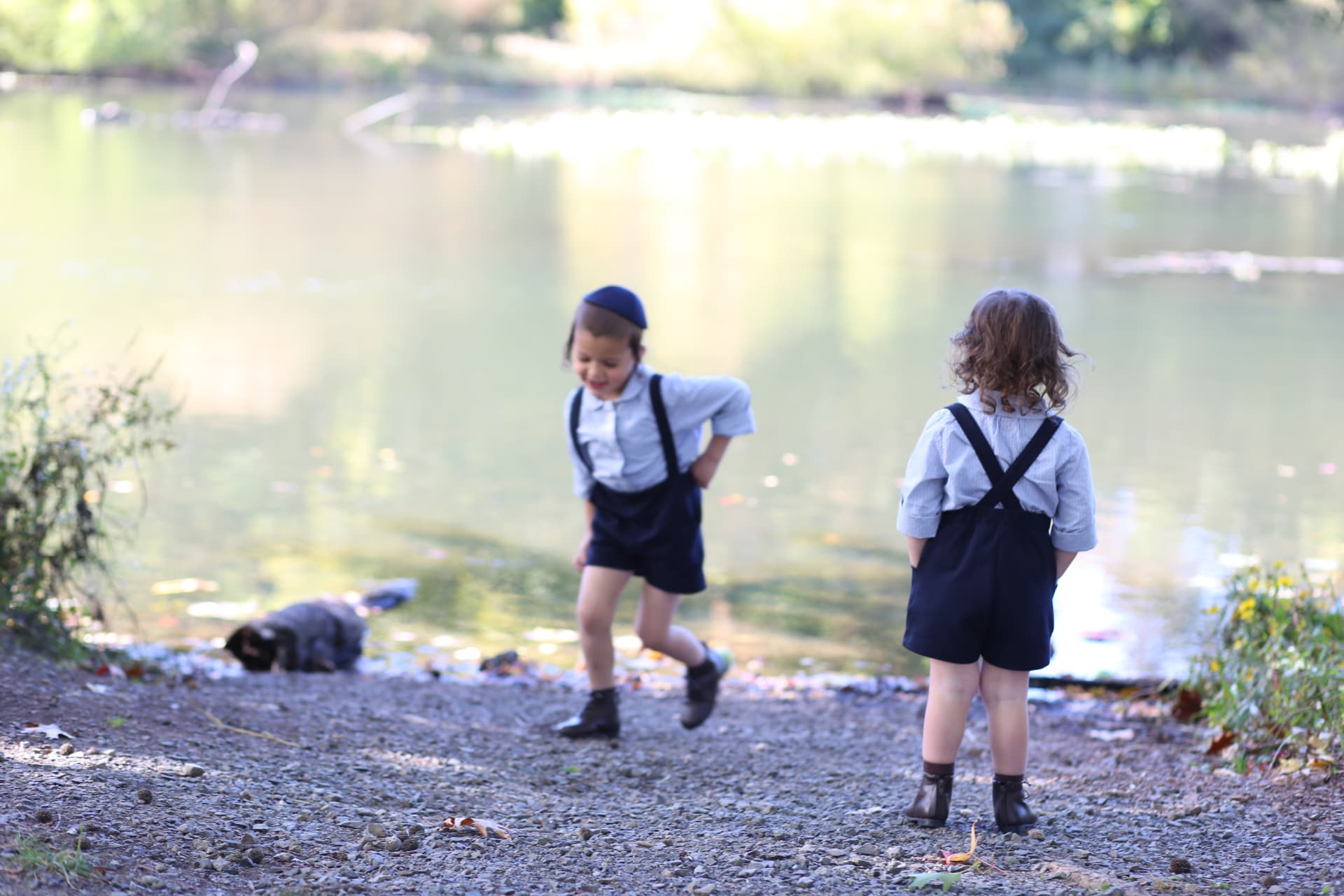 Two brothers in matching suspenders, one mid-laugh, one with hands in his pockets.