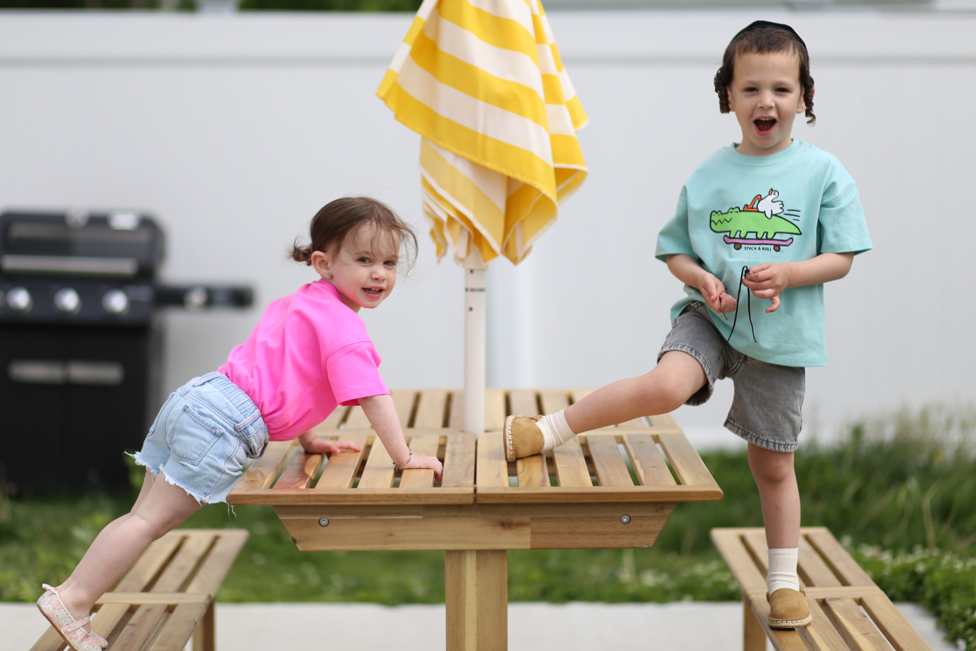 Two kids scrambling onto the backyard table.