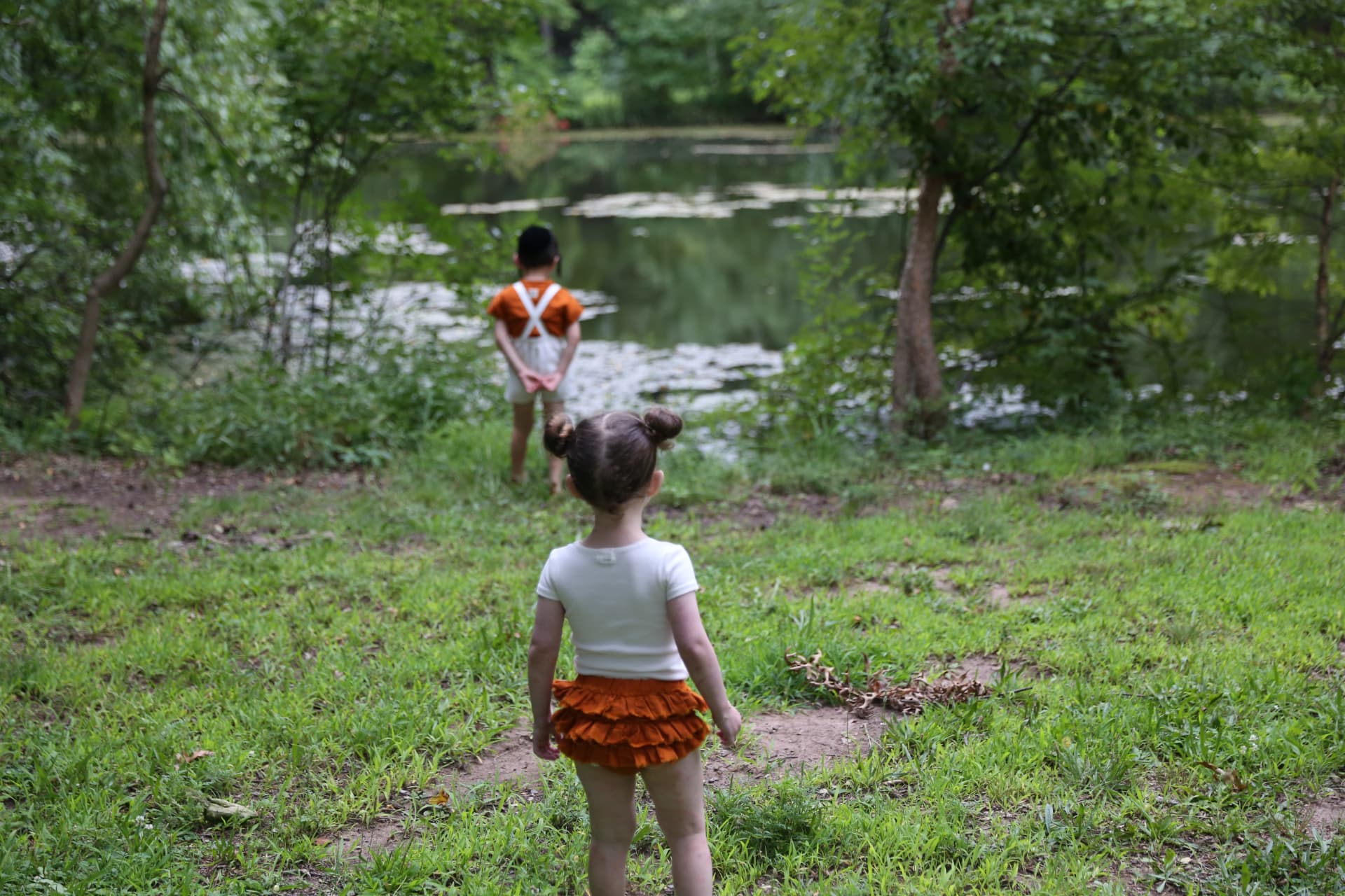 Children wandering toward a pond on a summer day.