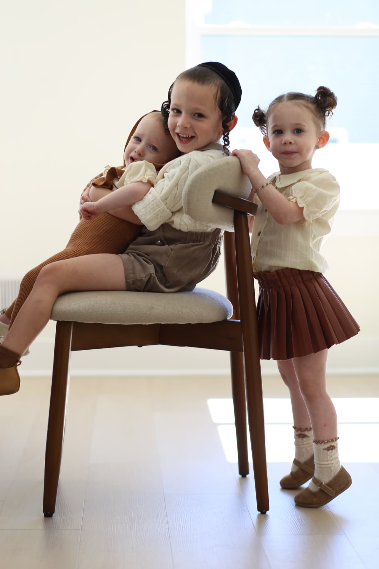 Three siblings crowded onto one chair.