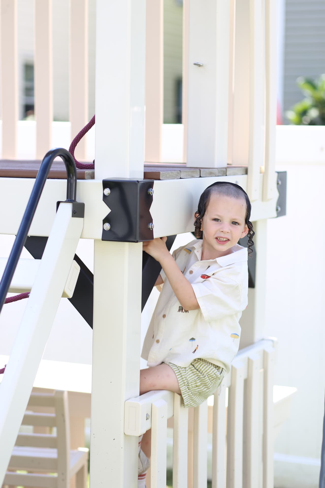 A smiling girl climbing a white playset.