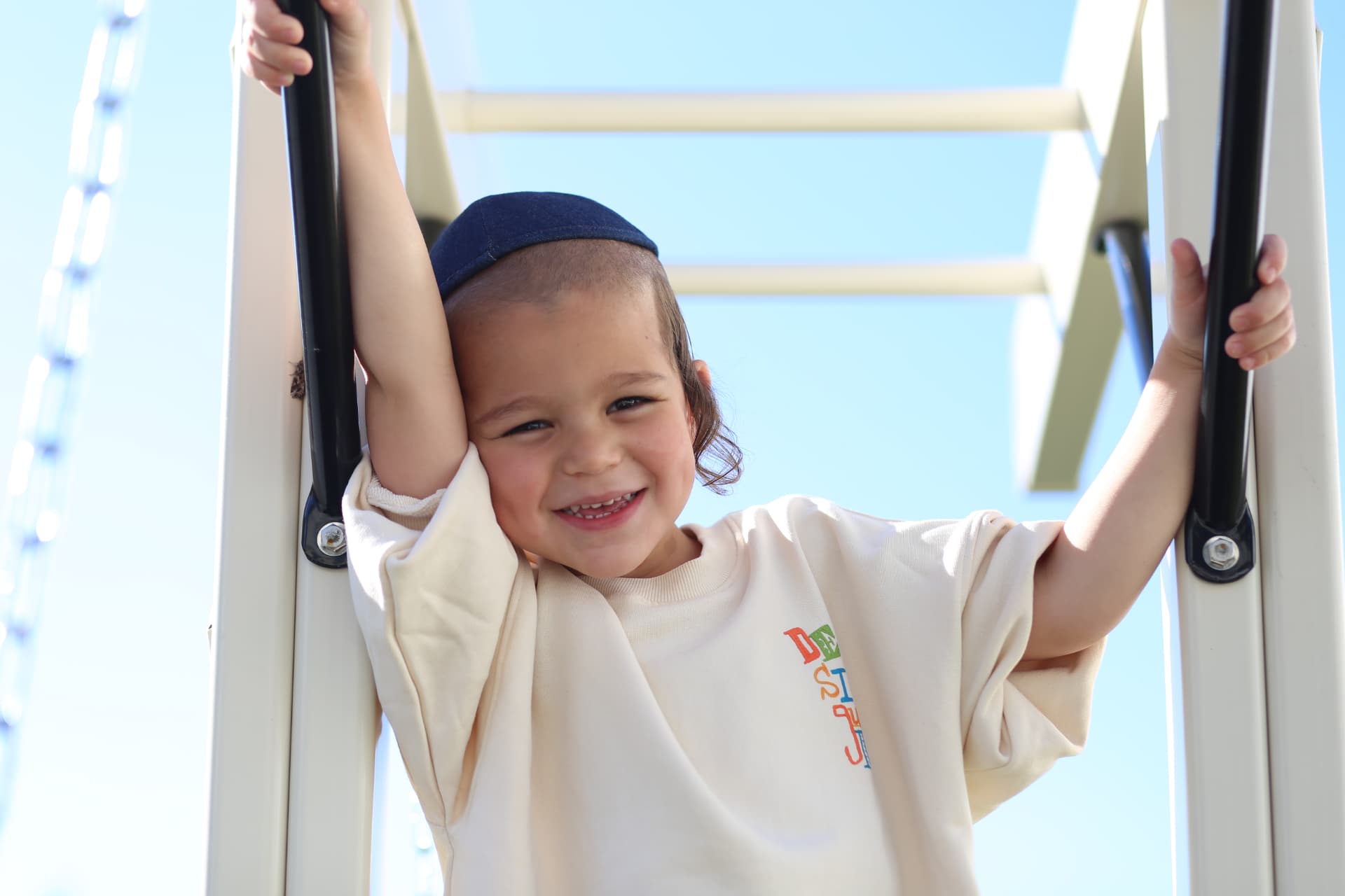 All smiles, hanging on at the top of the playset.