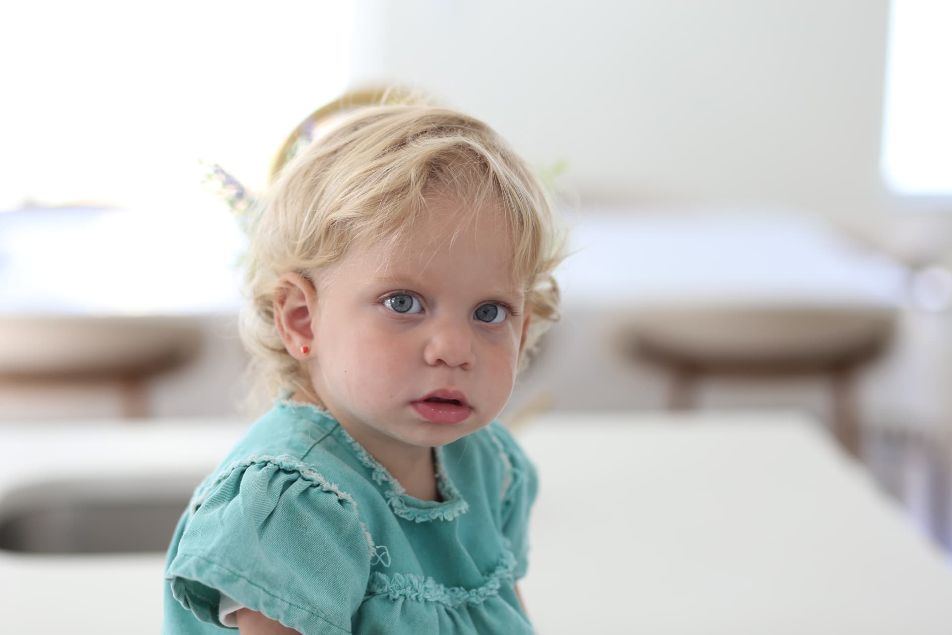 Blond curls and a teal dress in the kitchen.