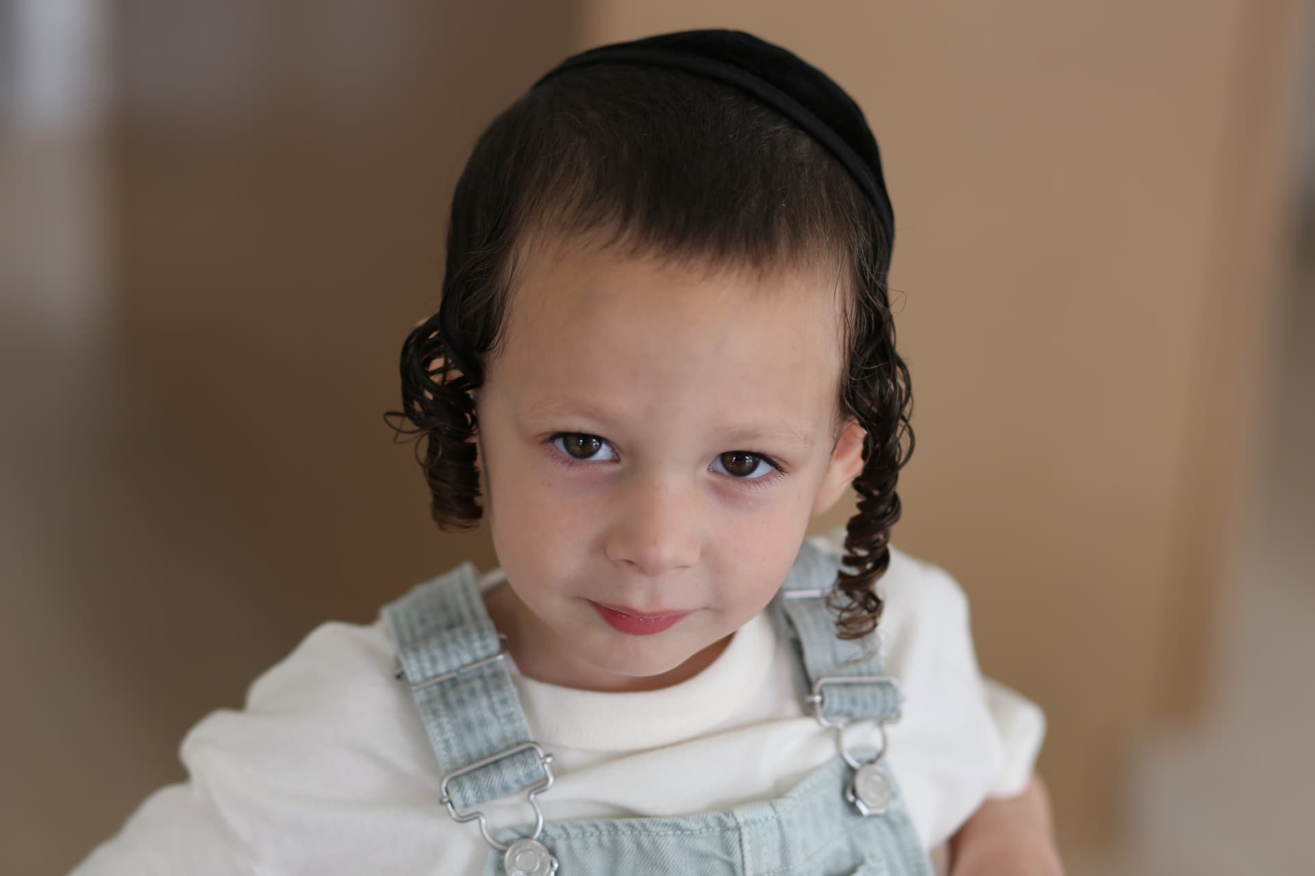 A steady look in white tee and overalls.