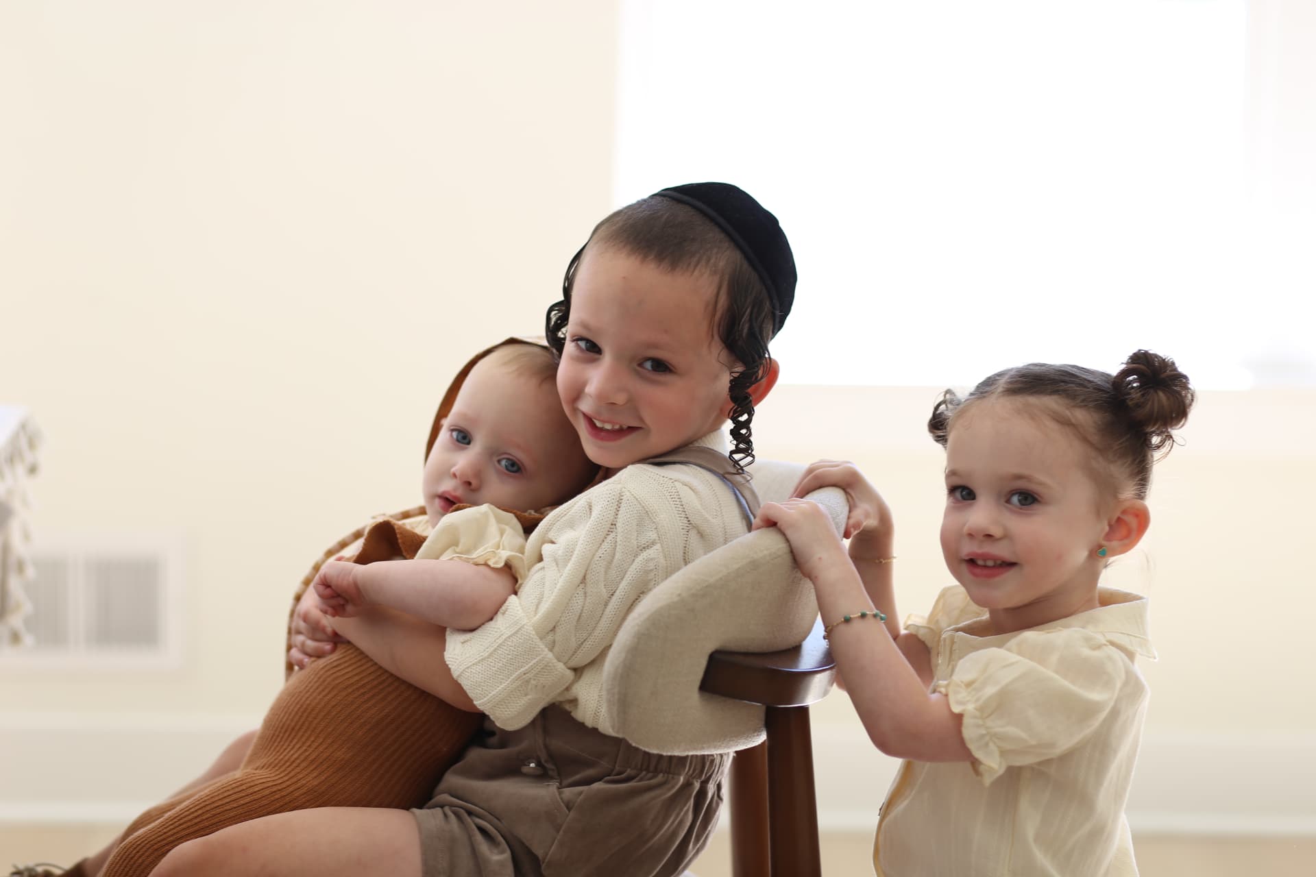 Holding the baby close, sister leaning in.