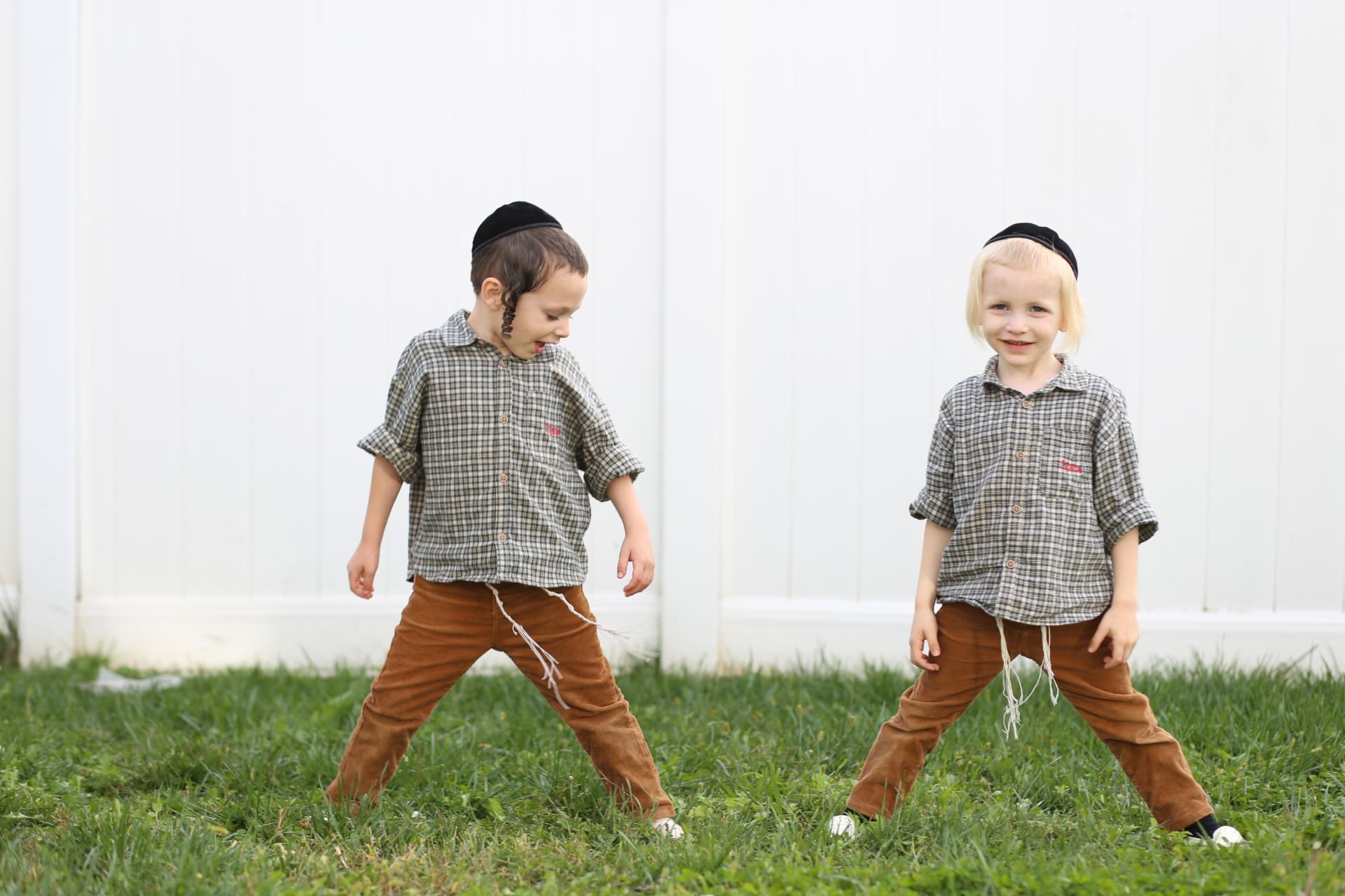 Two brothers in matching shirts on the lawn.