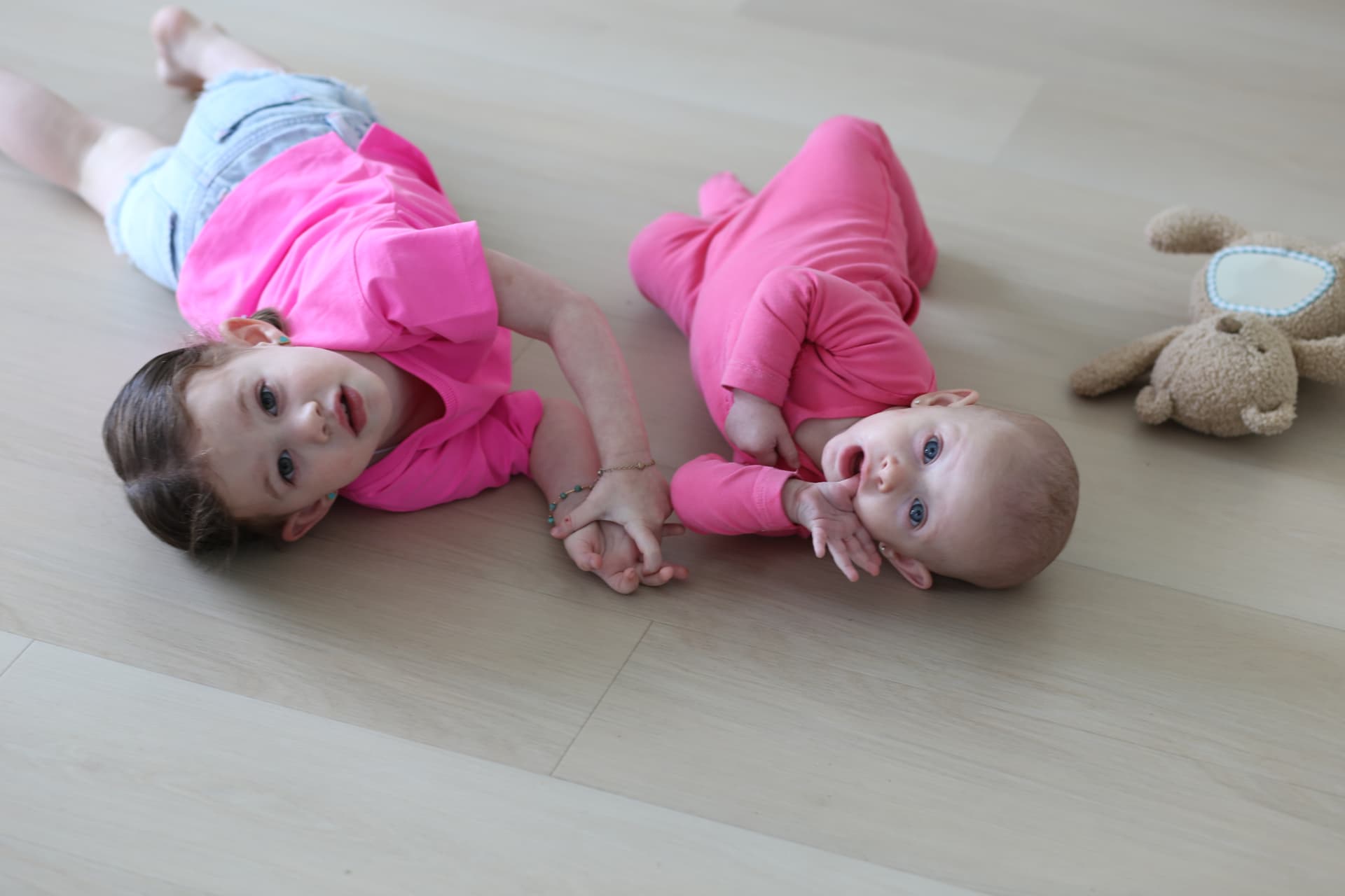 Big sister and baby, side by side on the floor.