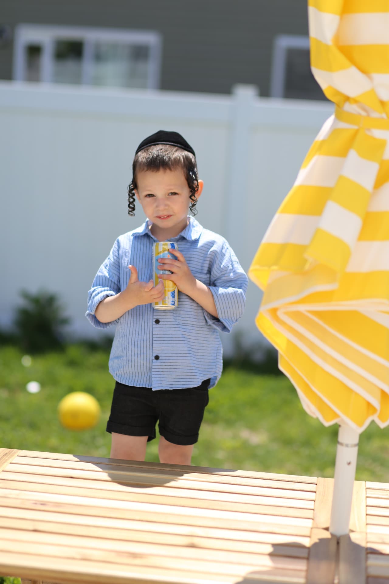 A boy and his can by the yellow umbrella.