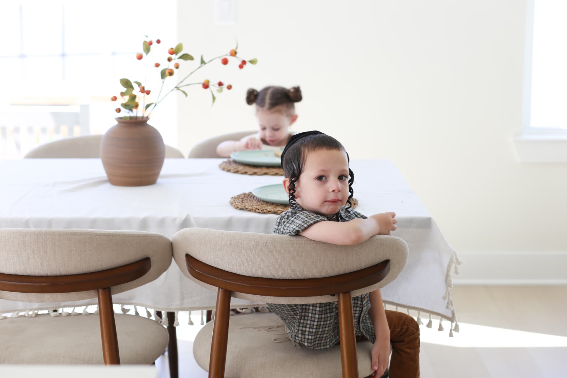 He turns around to check on us; she waits across the table.