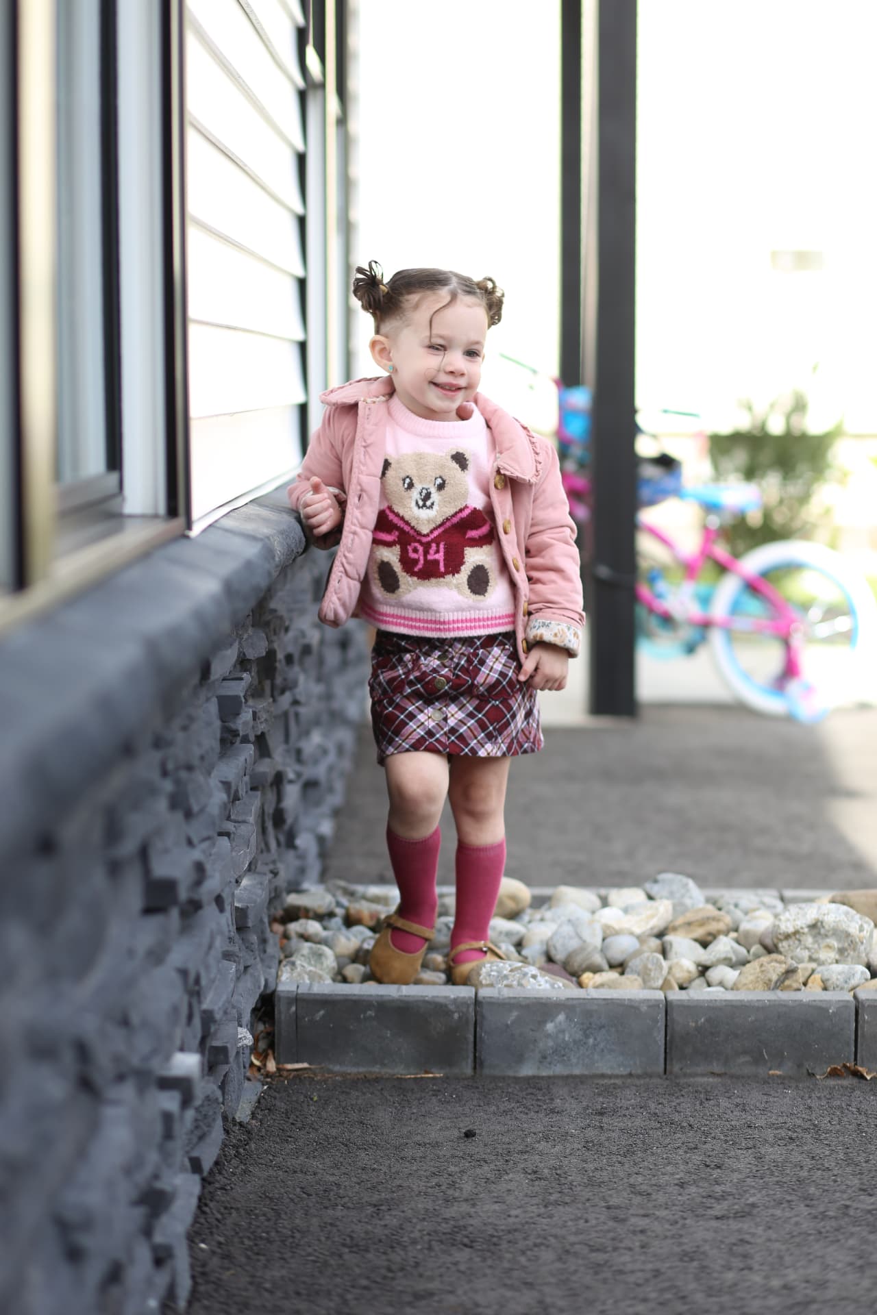 A little girl walking beside the house.