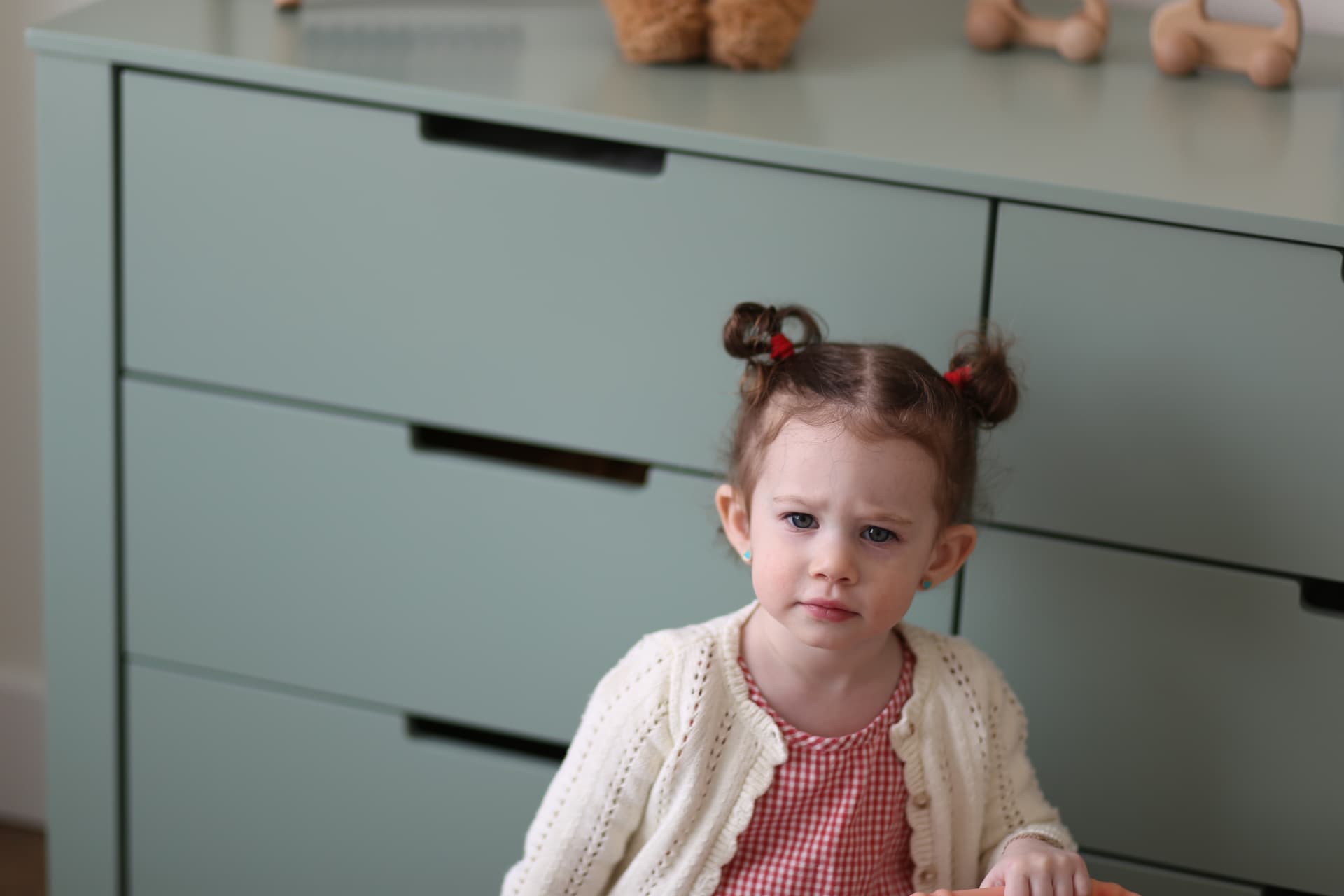 A serious little face in front of the dresser.