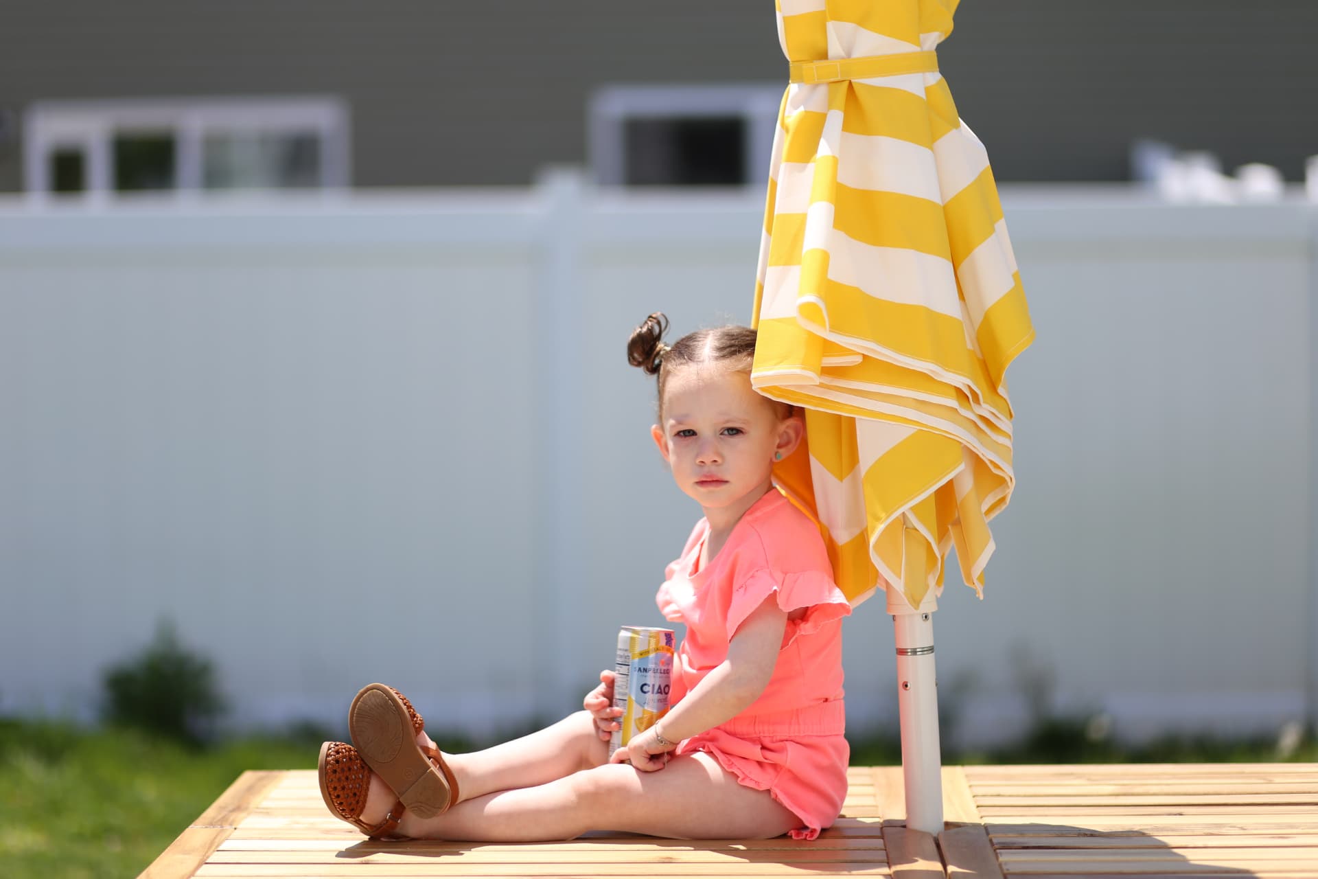 Sitting in the shade of the striped umbrella.