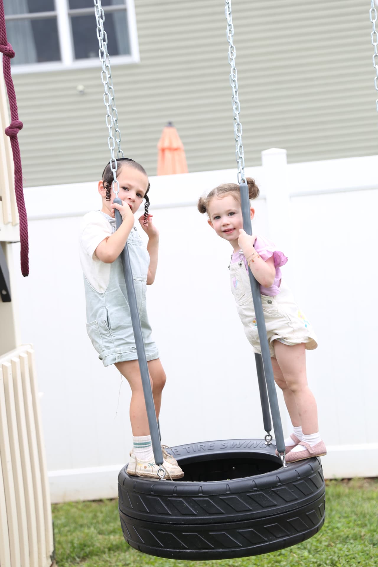 Two girls sharing a tire swing.
