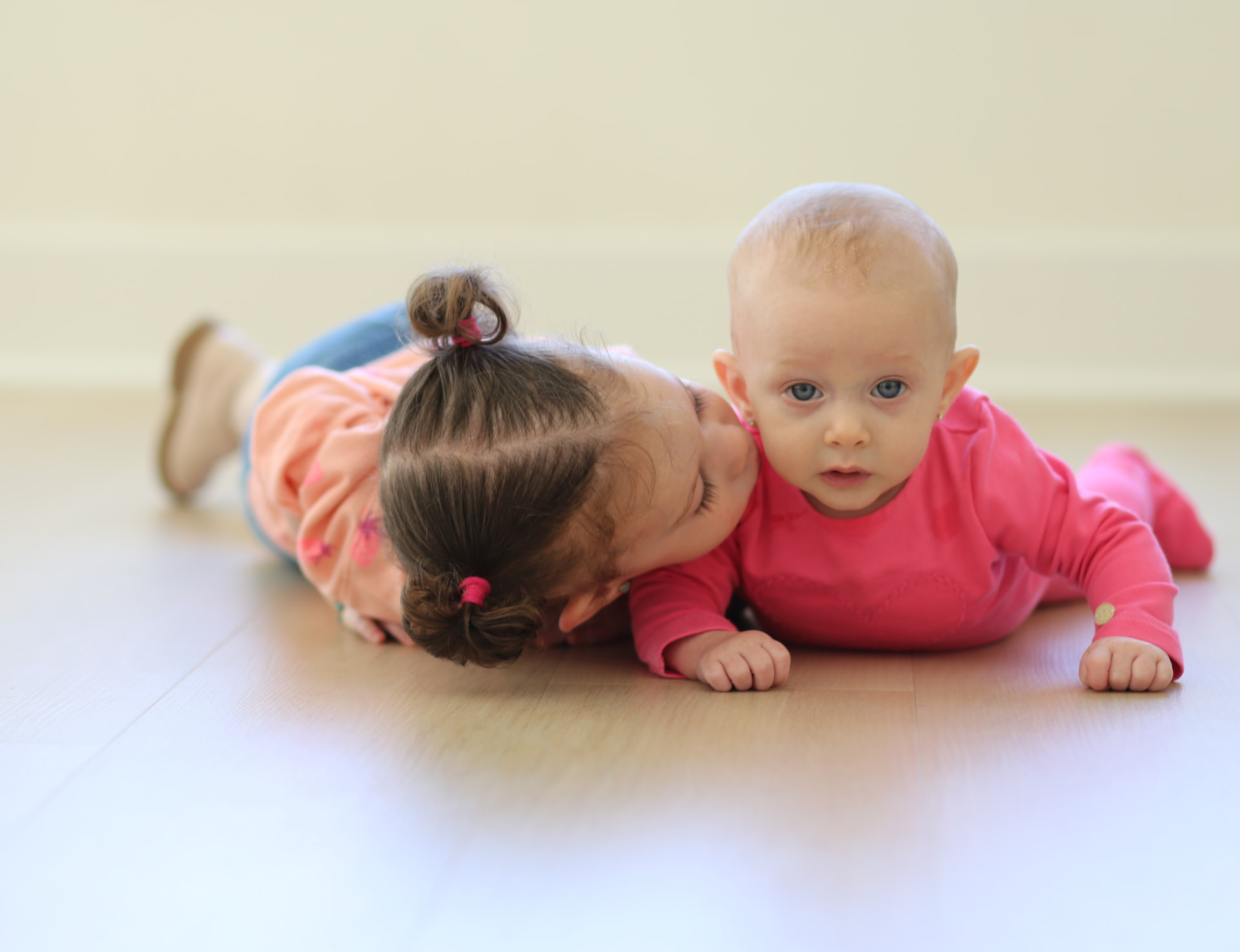 A big sister kiss on the living room floor.