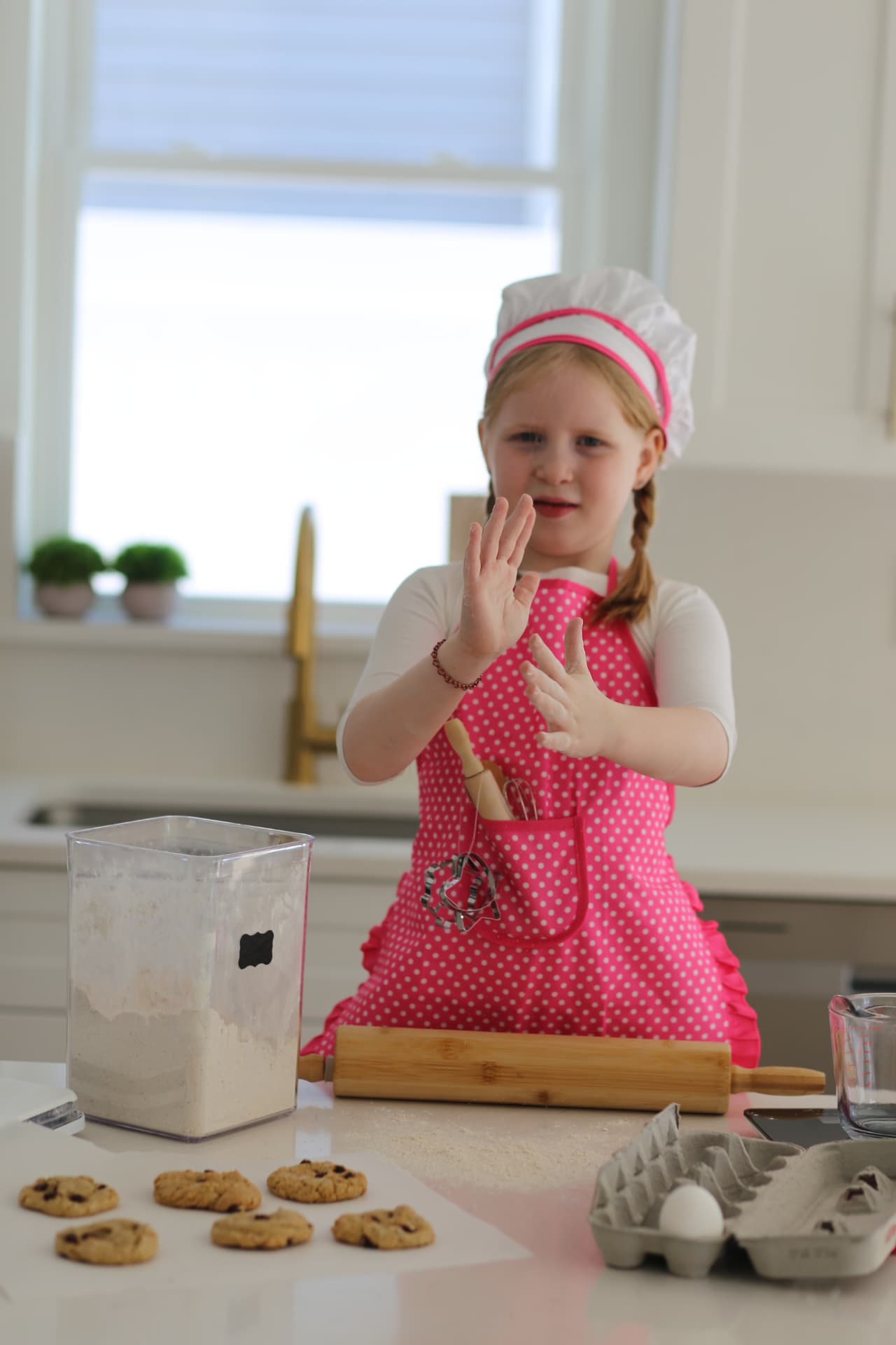 Flour on her palms, she shakes them off over the counter.